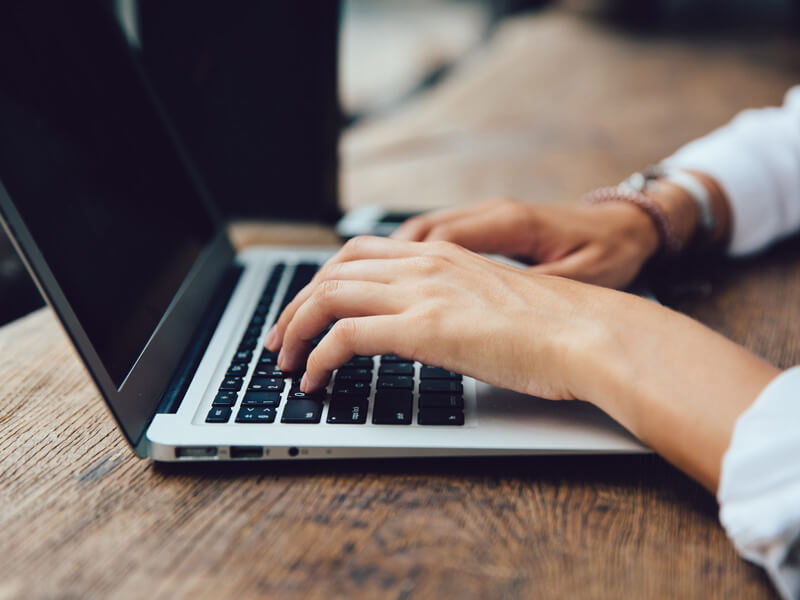 šake u položaju za kucanje na tastaturi laptopa