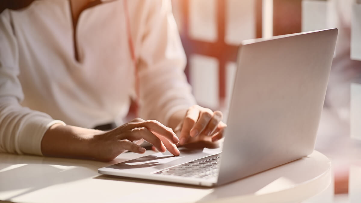 žena kuca na laptopu u prostoriji obasjanoj suncem